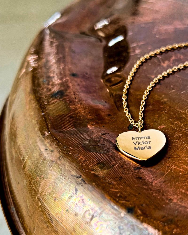 LUV QUOTE name necklace in gold-plated stainless steel with "Emma Victor Maria" engraved in a heart, on a patinated copper dish