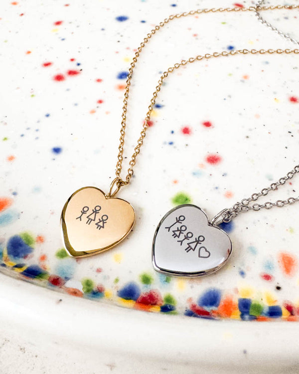 LUV STICK necklace in gold-plated and silver-coloured stainless steel, heart pendants engraved with matchstick figures, on speckled dish