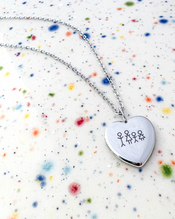 LUV STICK necklace in silver-coloured stainless steel with a matchstick family of four engraved in heart pendant, on speckled ceramic