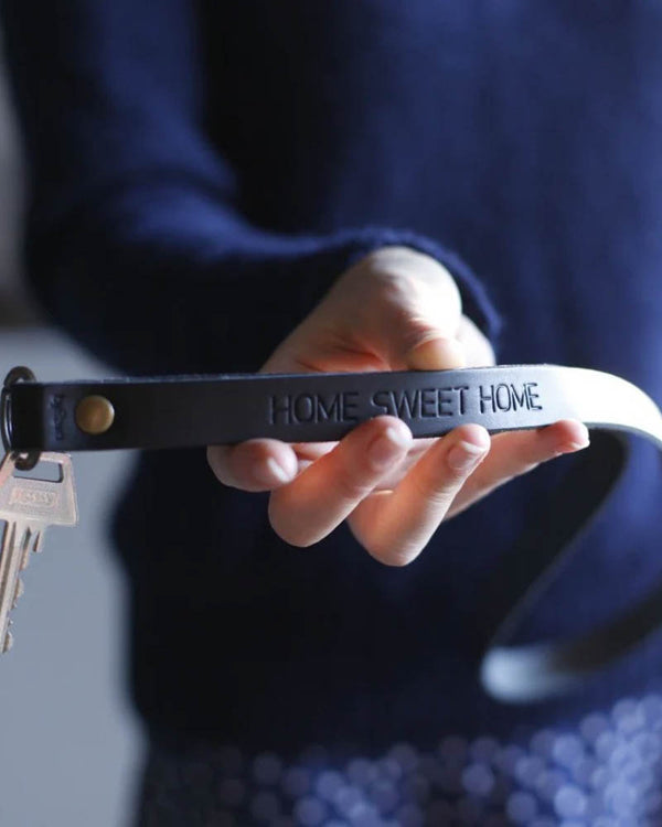 MAX leather keyring in black as a long strap with personalised engraving "Home sweet home", held in hand with keys