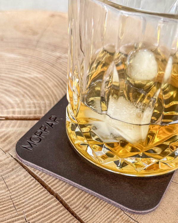 MOKKA square coaster in dark brown leather with the engraving "Morfar" under a crystal glass of whisky with ice