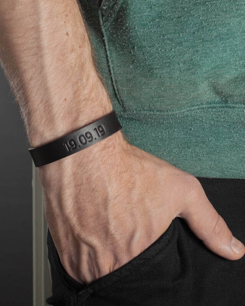 MONO leather bracelet in dark brown with the date "19.09.19" engraved on a man's wrist, green t-shirt
