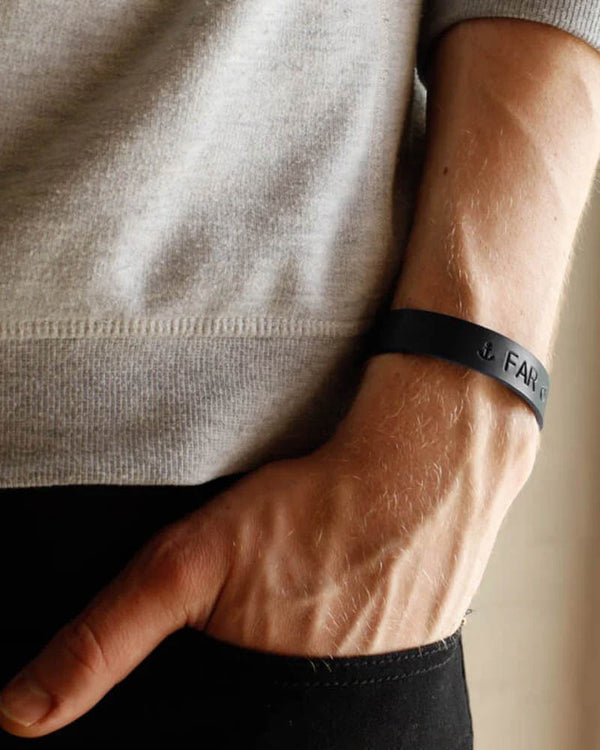 MONO leather bracelet in black with anchor symbol and the engraving "Far" on the wrist, hand in trouser pocket