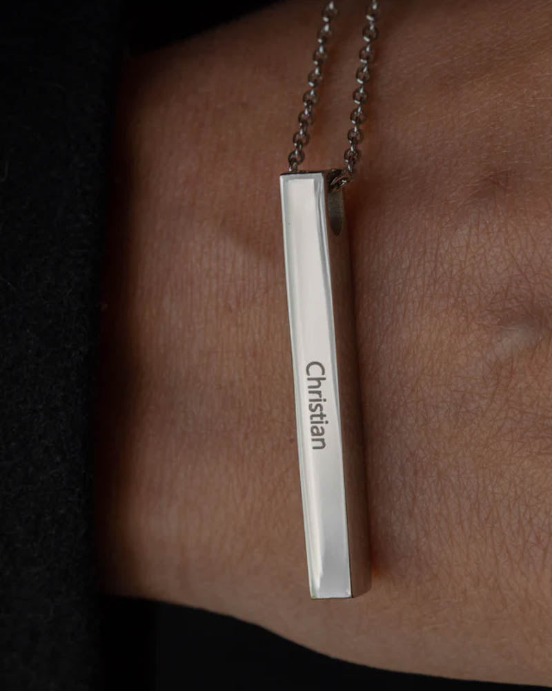 NEO name necklace in silver-coloured steel with the name "Christian" engraved on an elongated bar, worn around the neck over black clothing