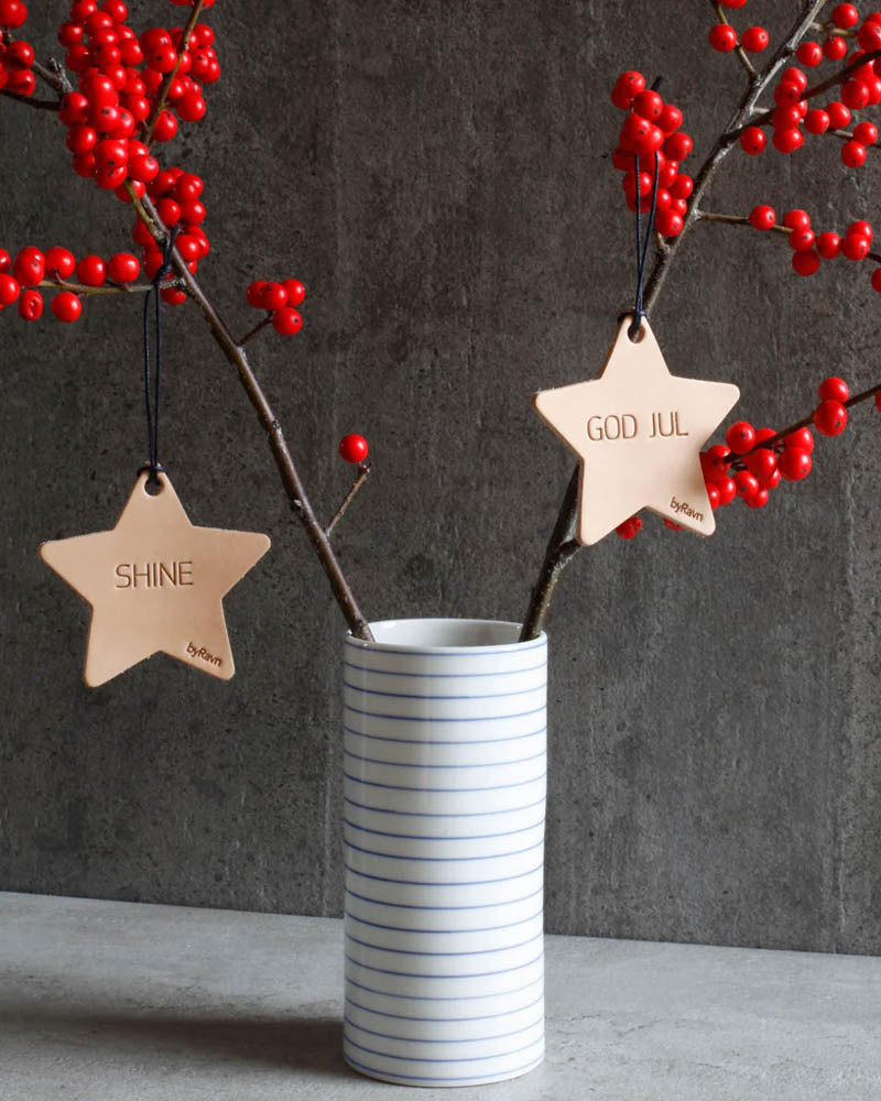 NORTH Christmas stars in natural leather with the engravings "Shine" and "God jul" hung on red berry branches in a striped vase