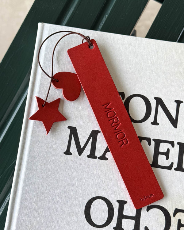 PAGE bookmark in red leather with the engraving "Mormor" and red heart and star on a cord, lying on a white book