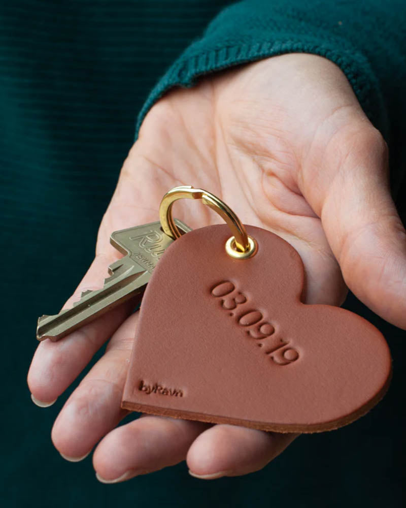 ROSE heart keyring in cognac leather held in hand with key and the date "03.09.19" engraved