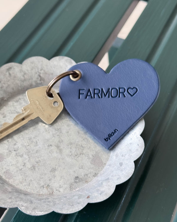 ROSE heart keyring in navy blue leather with the engraving "Farmor" ♡ and key in a zinc bowl on a green wooden bench