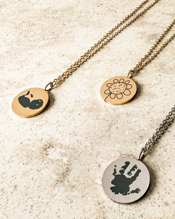 SIA MOTIF necklaces in silver-coloured and gold-plated steel engraved with handprint, ultrasound scan and flower drawing, on light stone