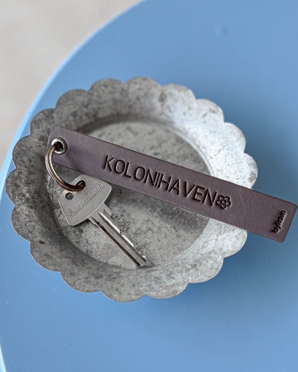SOLO Large keyring in dark brown leather with the engraving "Kolonihaven" and a flower, with key in a zinc bowl