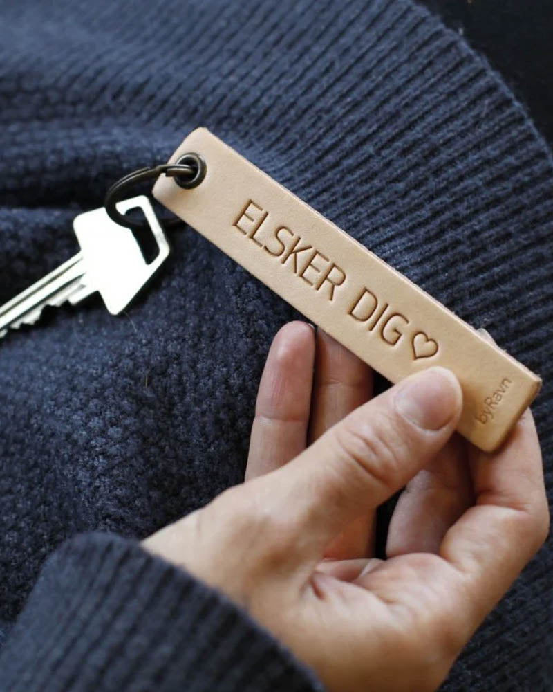 SOLO Medium keyring in natural leather held in hand with key and the engraving "Elsker dig" ♡