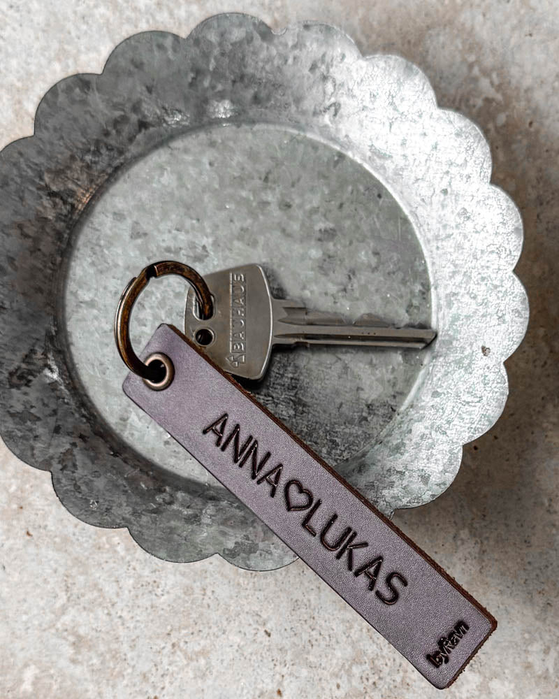 SOLO Medium keyring in dark brown leather with personalised engraving "Anna ♡ Lukas" and key in a zinc bowl
