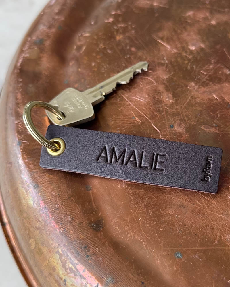 SOLO Small keyring in dark brown leather with the name "Amalie" engraved, gold-coloured ring and key on a copper tray