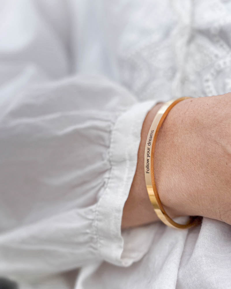 VENUS bracelet in gold-plated stainless steel with the engraving "Follow your dreams" with a white puff-sleeve blouse
