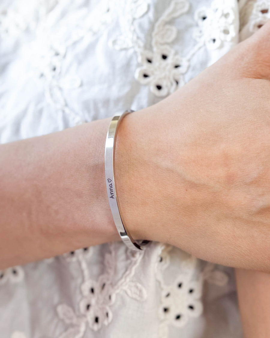 VENUS SCRIPT bracelet in silver-coloured stainless steel with the name "Anna" ♡ in script on the wrist, white embroidered blouse
