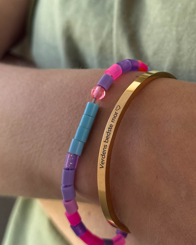 VENUS bracelet in gold-plated stainless steel with the engraving "Verdens bedste mor" ♡ worn with a colourful beaded bracelet
